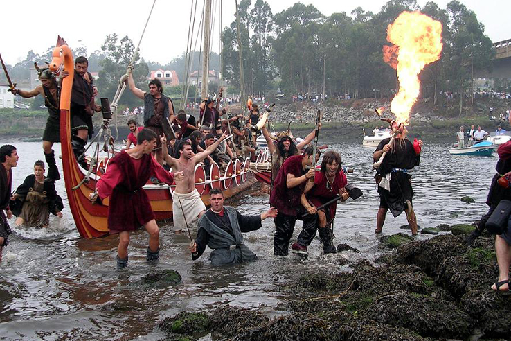 Drakkar landing at Catoira — warriors leaping into the water with a fire-breather behind